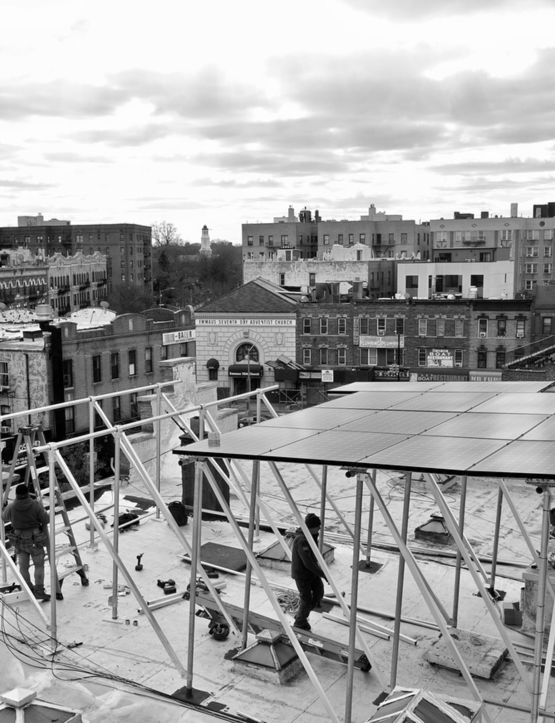 Kamtech Solar installation crew setting up solar panels on an urban rooftop, showcasing professional solar construction in a city environment.