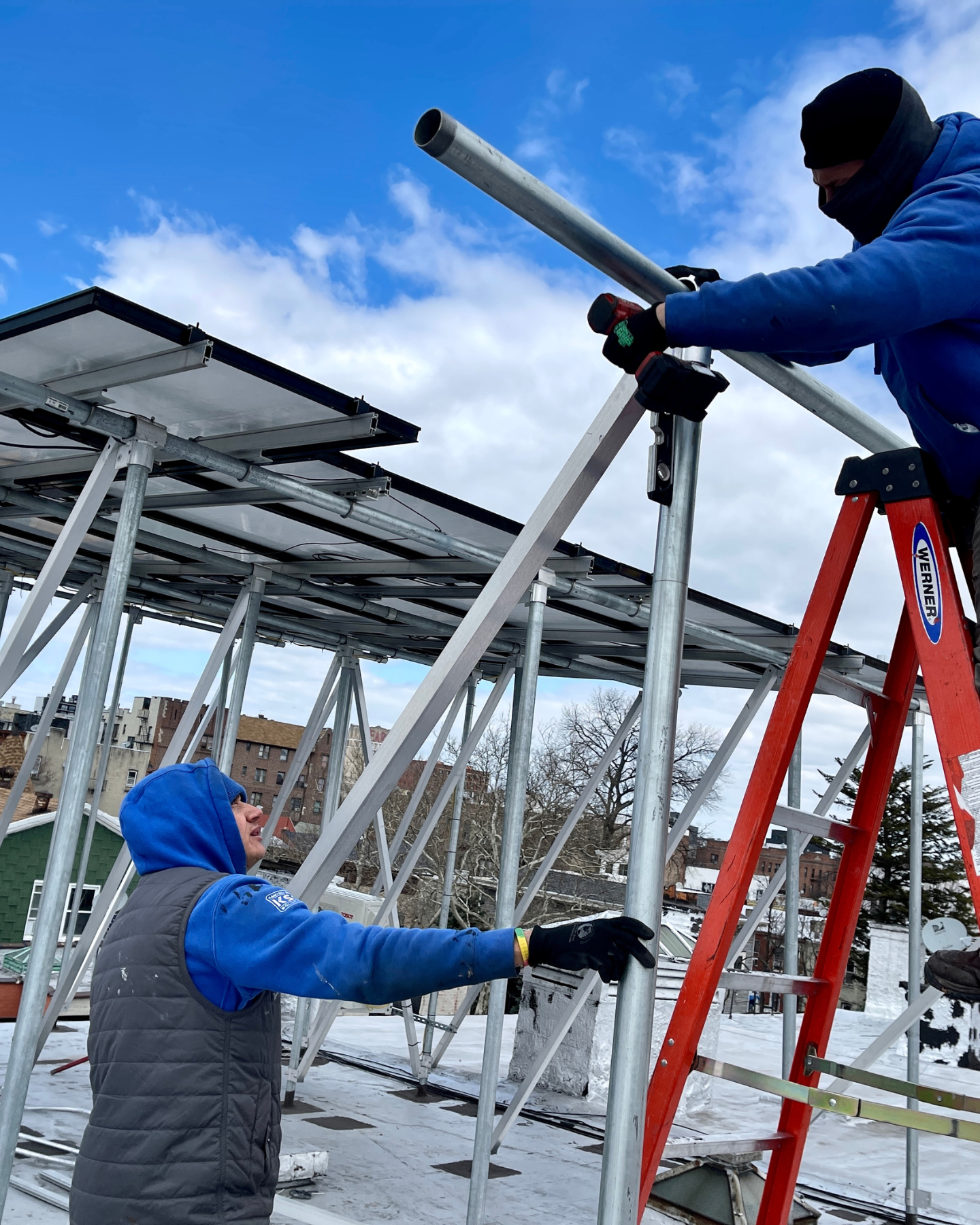 Kamtech Solar installation team assembling a solar panel racking system on the rooftop, showcasing expert craftsmanship, durable framework, and professional clean energy construction. Outside Photo Of Kamtech Solar Building with 2 company vehicles parked in the front