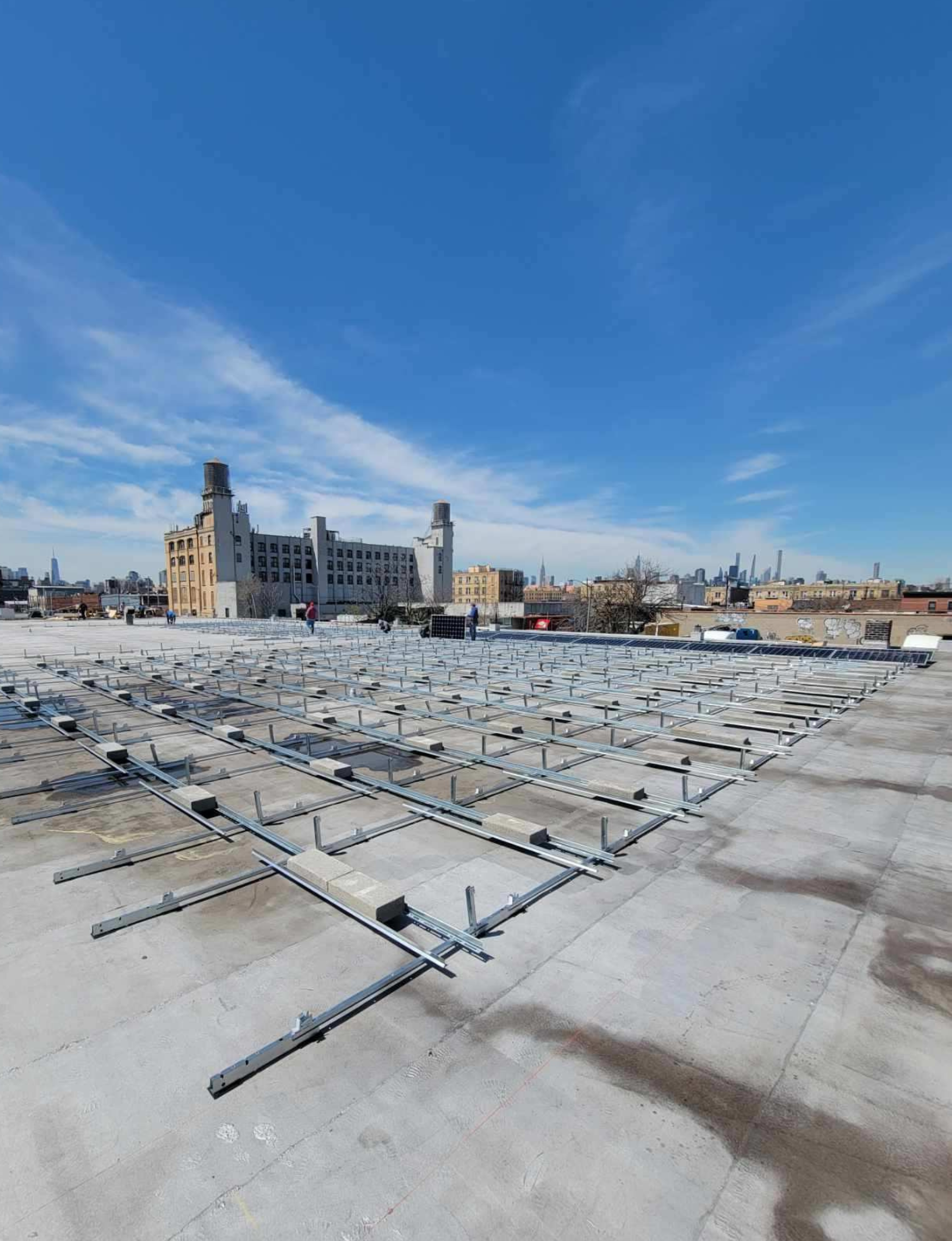 Kamtech Solar before image showing a commercial rooftop with metal mounting racks installed for upcoming solar panel placement.